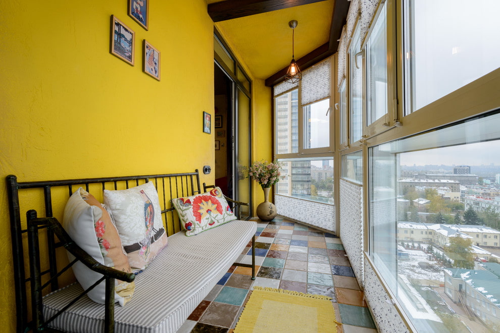 Узкая скамейка вдоль желтой стены балкона