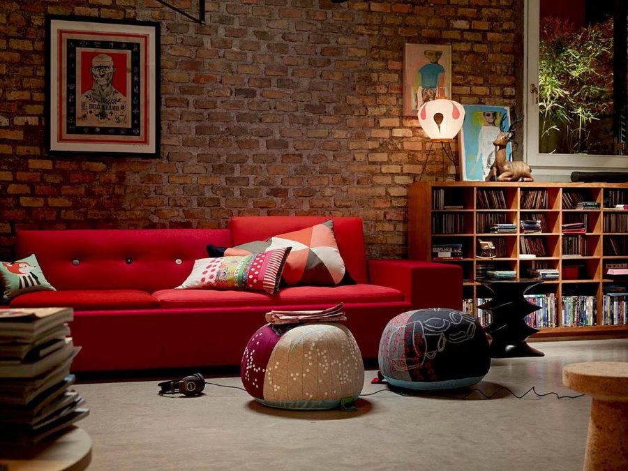 Красный диван в комнате с имитацией кирпичной стены